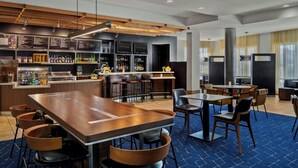 A modern hotel lobby with a bar area, seating arrangements, and a counter with various amenities. - Courtyard by Marriott Evansville East (Evansville)