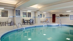 Una piscina interior con borde de azulejos, sillas de descanso y una puerta.