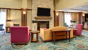 Un vestíbulo de hotel con chimenea de piedra, una televisión de pantalla plana y asientos cómodos.