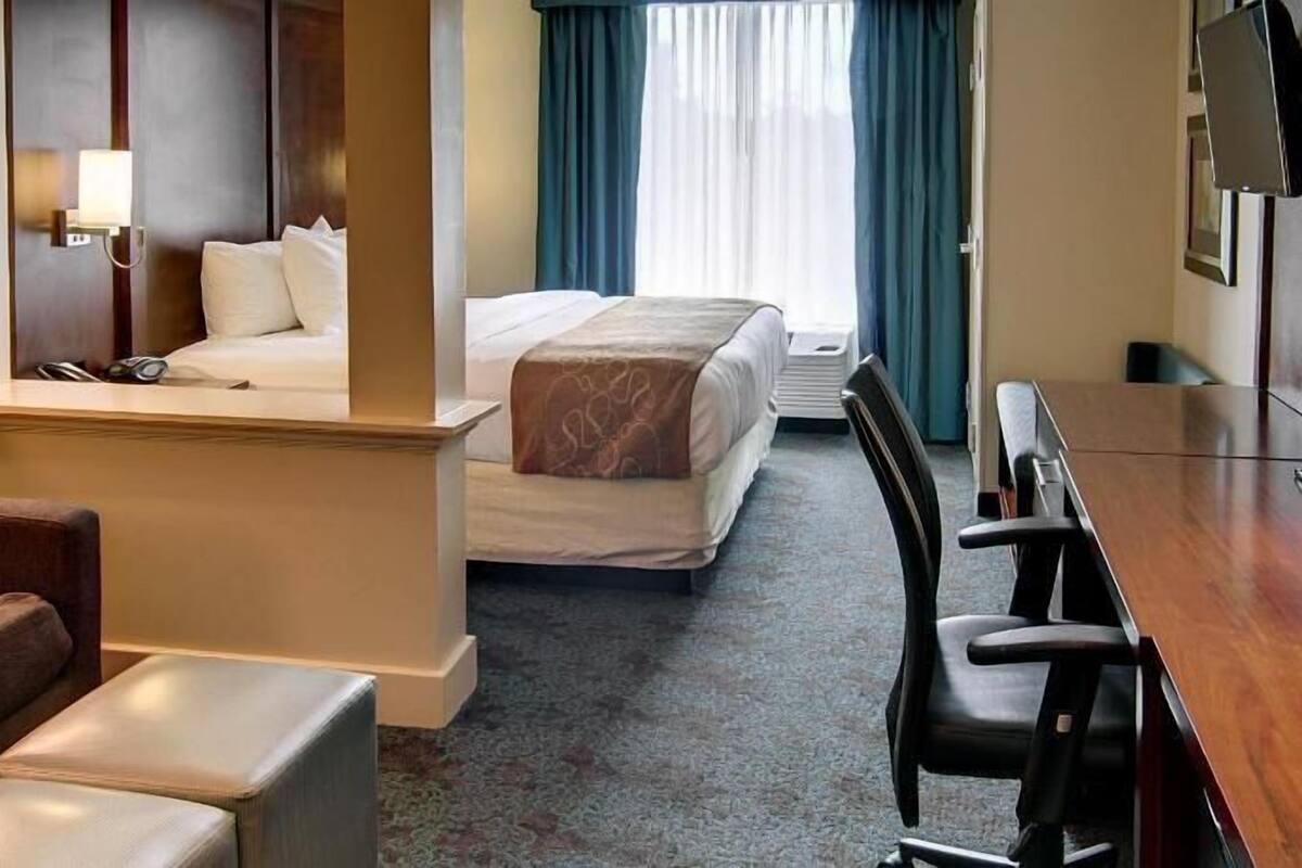 Een hotelkamer met een bed, een bureau, een stoel, een bank en een televisie.