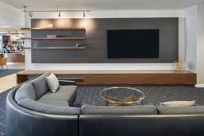 A modern living room with a large flat-screen TV, built-in shelves, a sectional sofa, and a glass coffee table.
