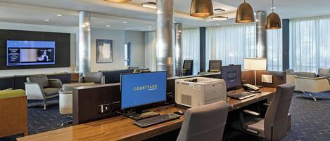 A modern hotel lobby with a reception desk, comfortable seating, and a large screen displaying a movie.