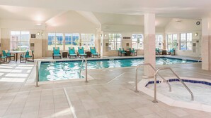Un hall d’hôtel doté d’une piscine, de coins salon et d’un panneau indiquant « Il est interdit de plonger ».