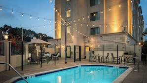 A swimming pool with a tiled edge, surrounded by outdoor seating and string lights. - Residence Inn San Diego Del Mar (San Diego)