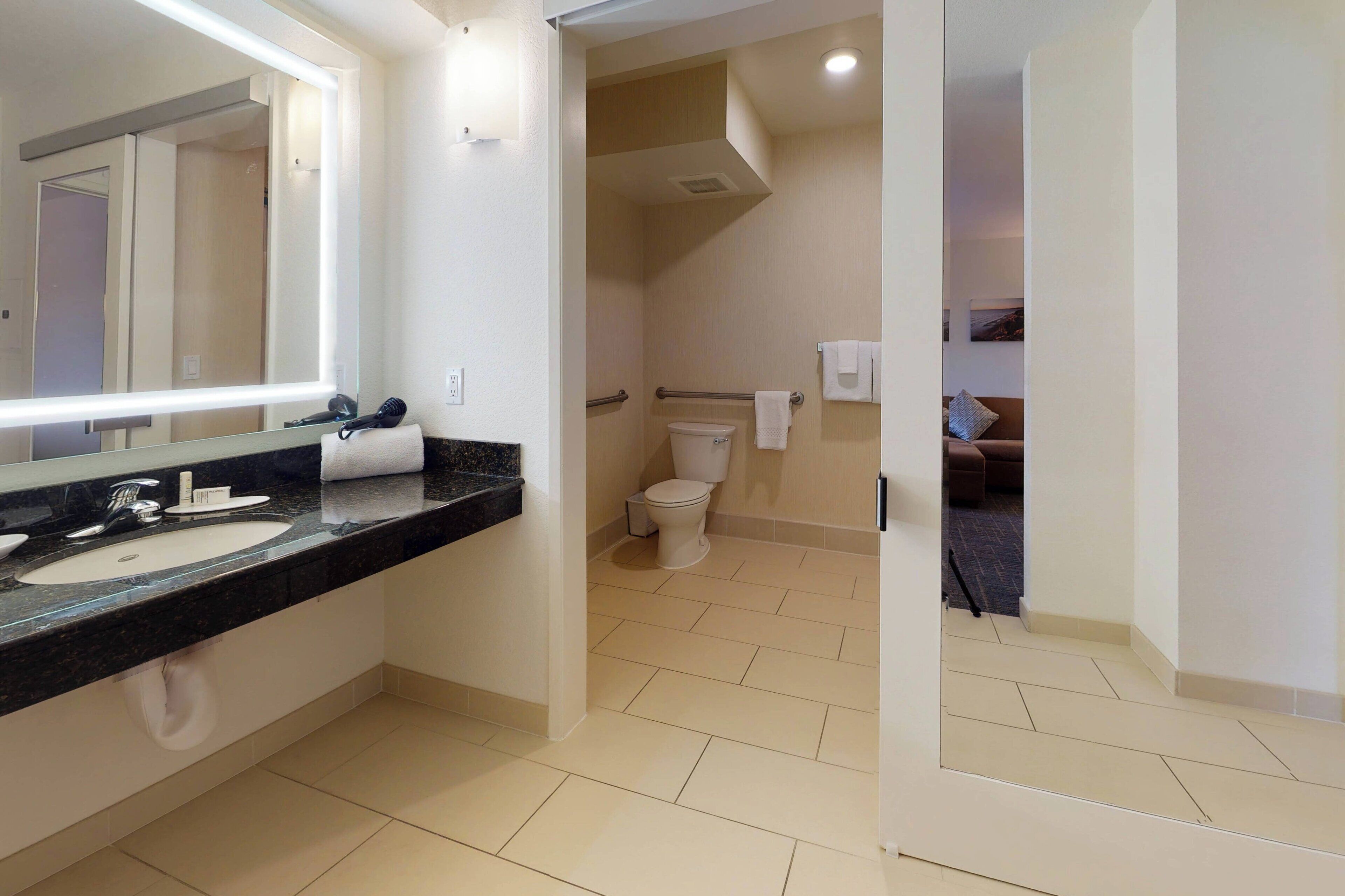 Une salle de bain moderne avec un grand miroir, un lavabo et des toilettes.