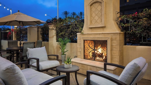 An outdoor seating area with chairs and tables, a fire pit, and a decorative wall. - Residence Inn San Diego Del Mar (San Diego)