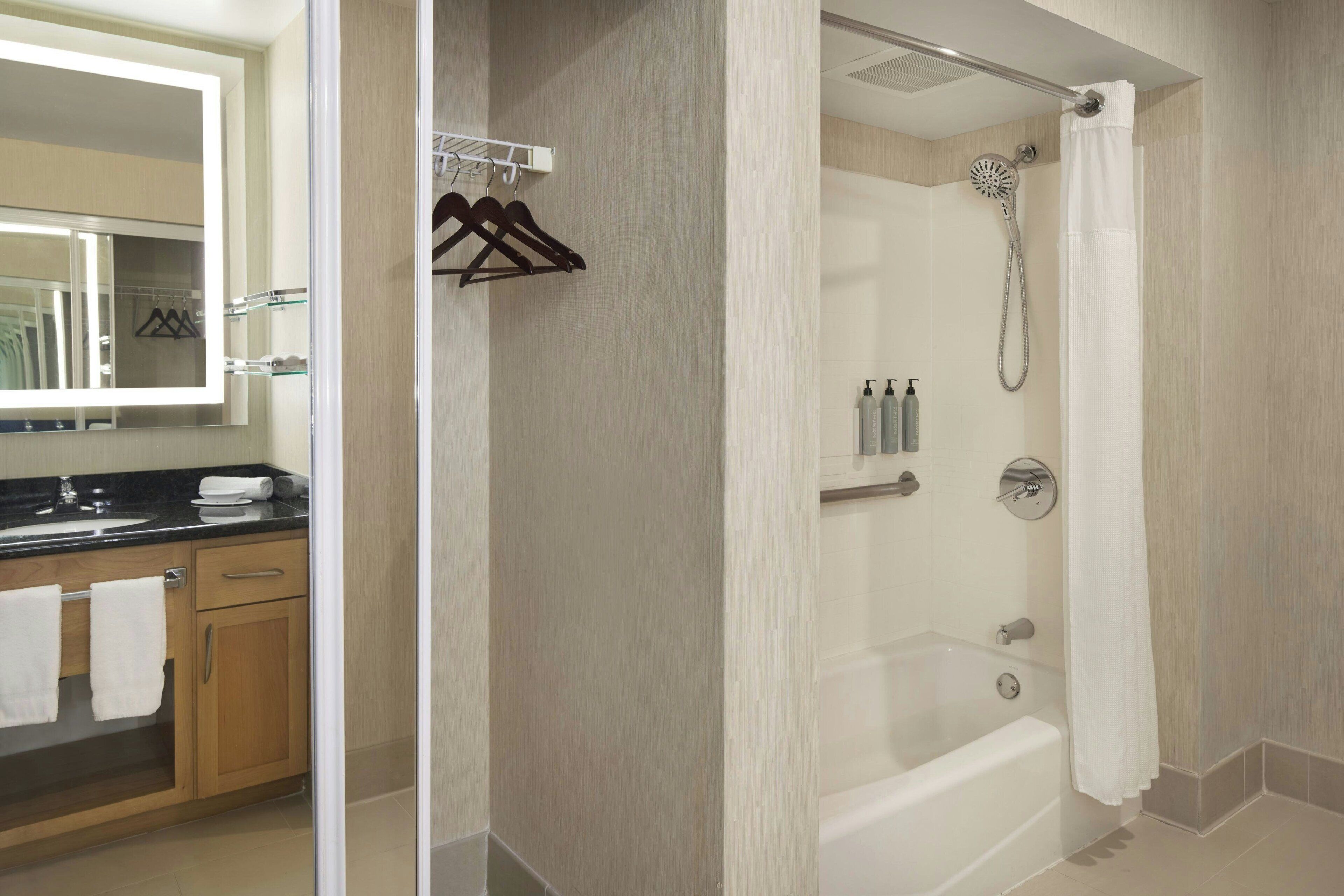 Une salle de bain moderne avec une douche à parois de verre, un meuble-lavabo avec un miroir et un porte-serviettes.
