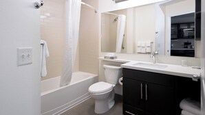 A modern bathroom with a bathtub, toilet, and vanity. - Candlewood Suites Greeley by IHG (Greeley)
