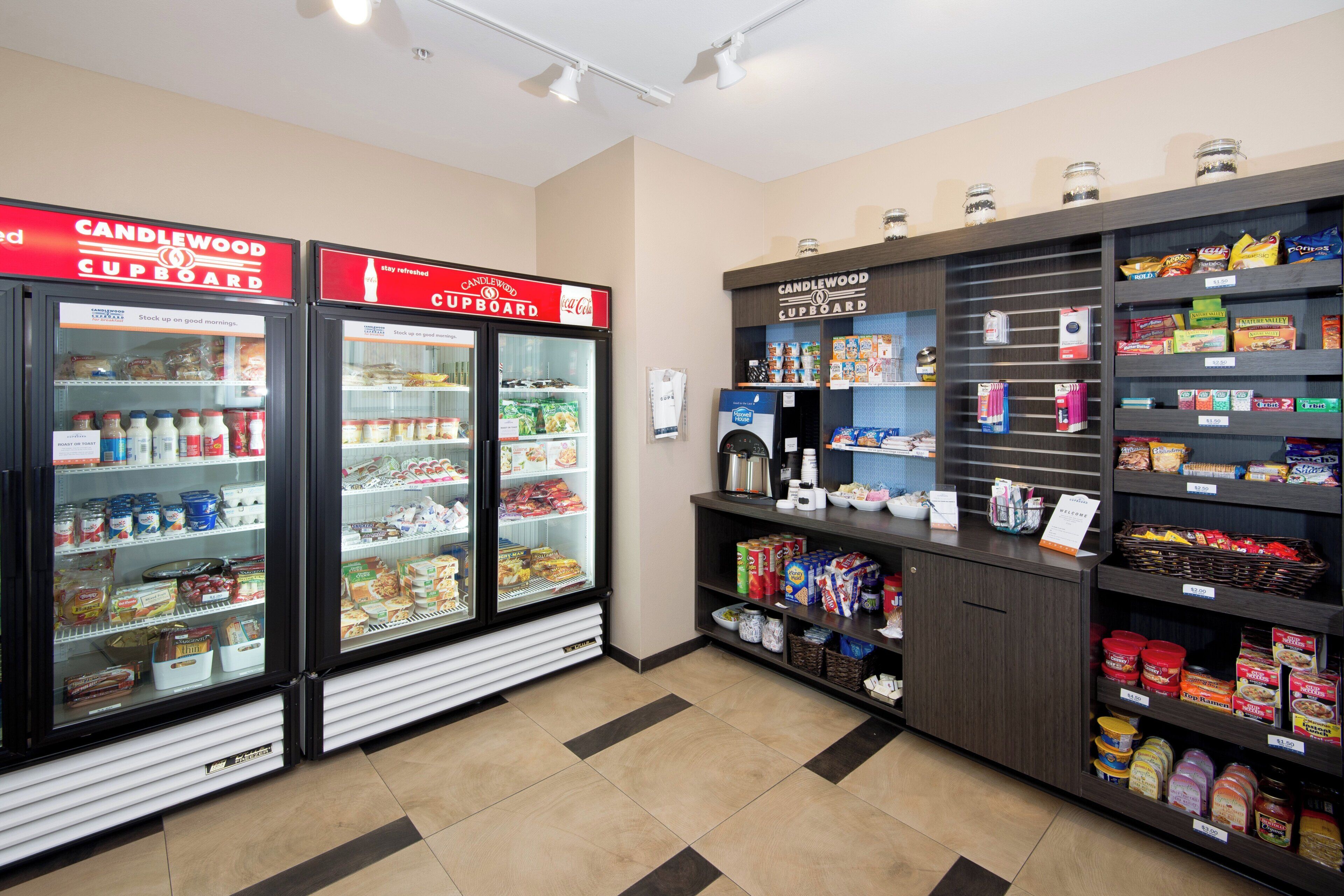 Une épicerie de proximité dotée de rayons réfrigérés, d’étagères remplies d’en-cas et de boissons, et d’une machine à café.