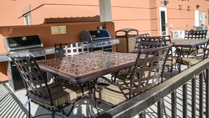 An outdoor patio with a grill, table, and chairs. - Candlewood Suites Greeley by IHG (Greeley)