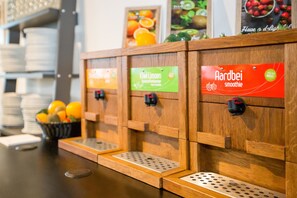 A juice bar with wooden dispensers labeled 'Kiwi Limon' and 'Aardbei smoothie'. - Tulip Inn Eindhoven Airport (Eindhoven)