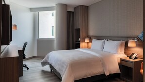 Una habitación de hotel moderna con una cama grande, lámparas de noche, un escritorio y una silla.