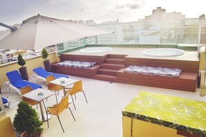 Una terraza en la azotea con sillones de descanso, una bañera de hidromasaje y un comedor.