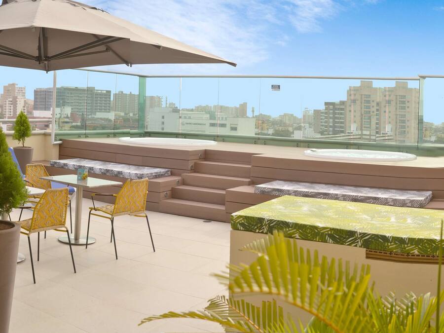 Una terraza en la azotea con asientos al aire libre, un paraguas grande y vistas de la ciudad.
