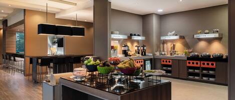 A modern kitchen with a central island, bar area, and breakfast buffet.