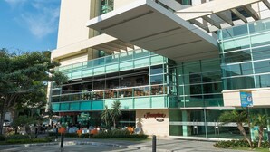 Un hotel moderno con fachada de vidrio, zona de estar al aire libre y un llamativo letrero con el nombre "Hampton".