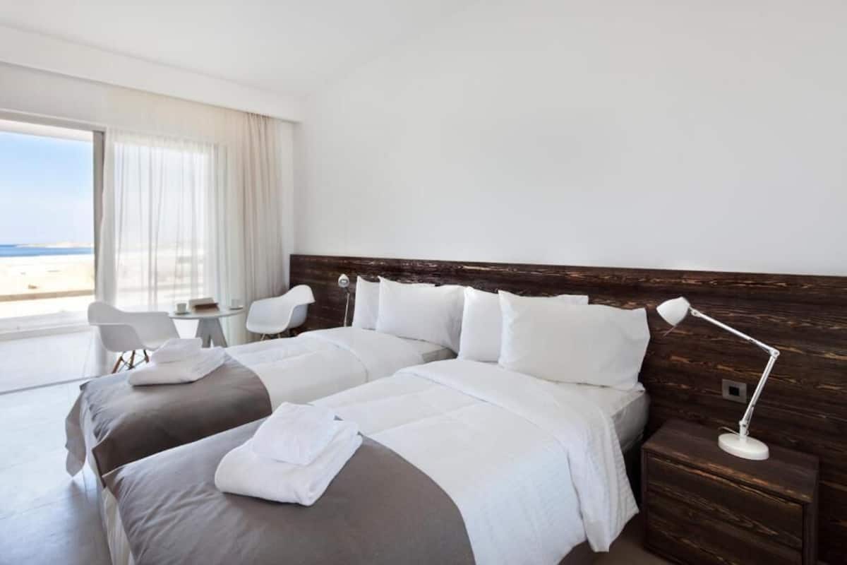 Une chambre d’hôtel moderne avec un grand lit, une table de chevet, un bureau et une chaise.
