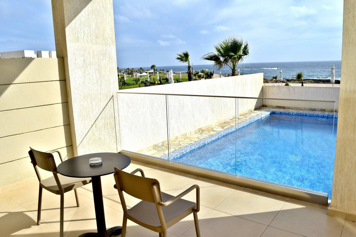 Un balcon avec une piscine, des chaises et une vue sur l’océan.