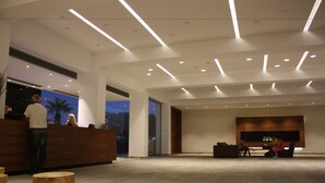 A spacious lobby with a reception desk, seating area, and a large wall-mounted display. - Amphora Hotel & Suites (Paphos)