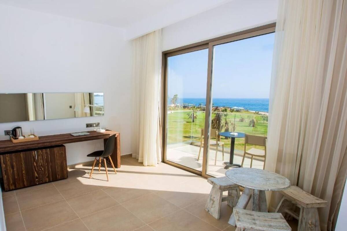 Un balcon avec vue sur l’océan et un coin repas comprenant une table et des chaises.