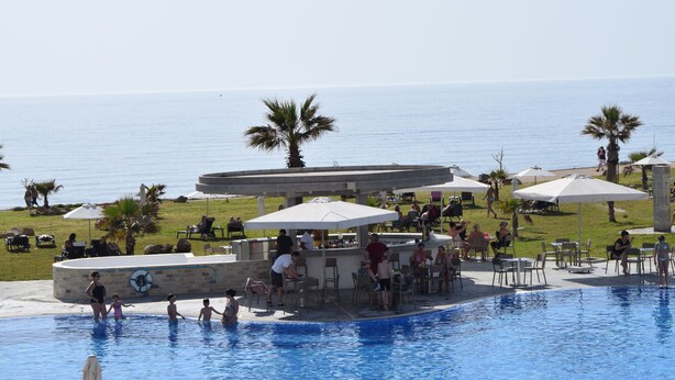 A pool area with a bar and seating, overlooking the sea. - Amphora Hotel & Suites (Paphos)