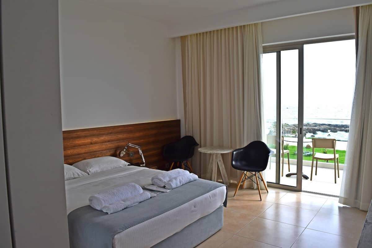 Une chambre d’hôtel avec un lit, une petite table, deux chaises et une vue sur l’extérieur grâce à une porte coulissante.