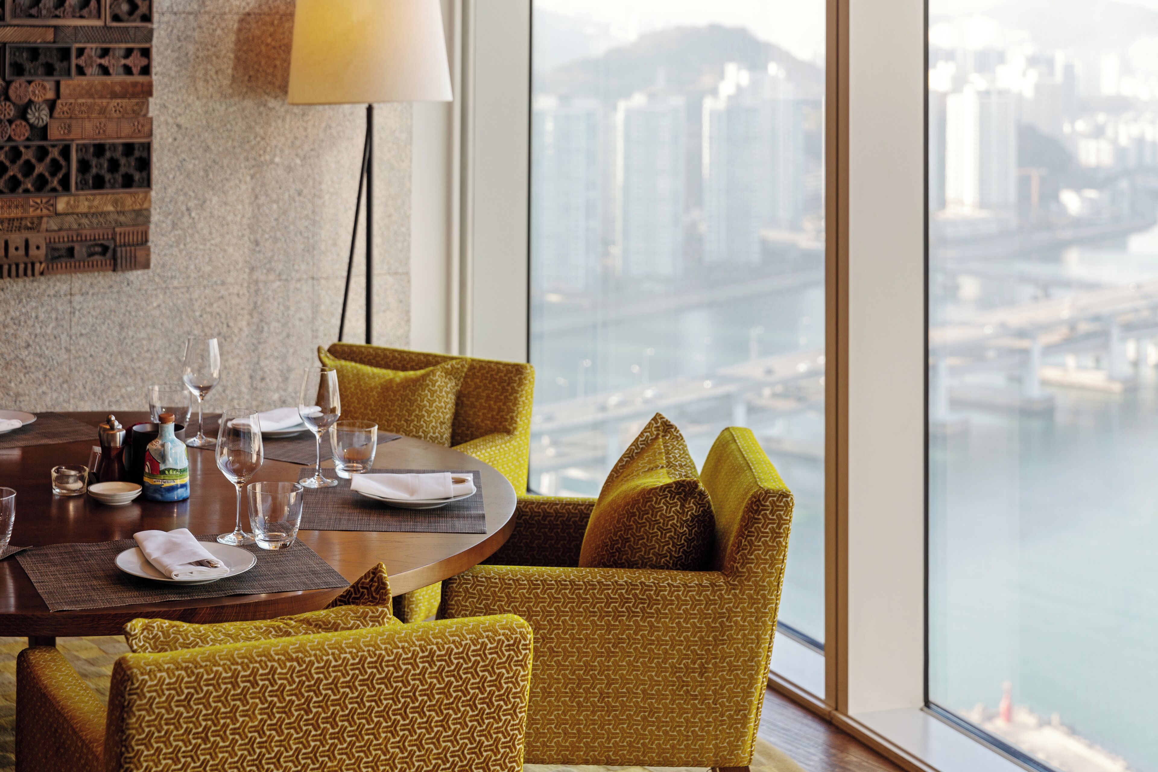 A dining area with a table set for two, a city view, and a patterned wall.