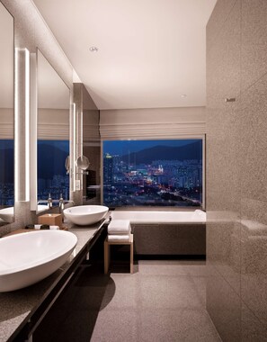 A modern bathroom with two large sinks, a large mirror, and a view of a cityscape at night.