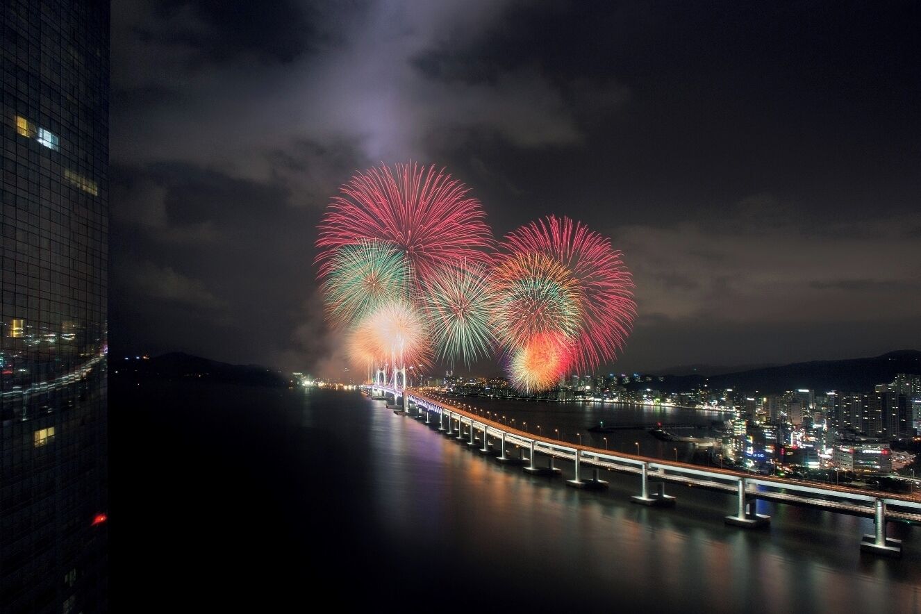 A nighttime cityscape with a bridge and fireworks display.