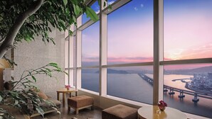 A modern room with a large window, a sofa, a round table, and a potted plant. - Park Hyatt Busan (Busan)