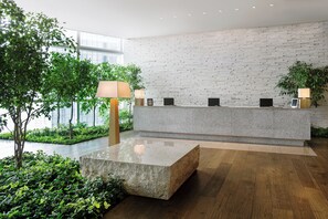 A reception area with a stone counter, wooden flooring, and indoor plants.