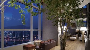 A modern interior with a large window, a seating area, and a tree. - Park Hyatt Busan (Busan)