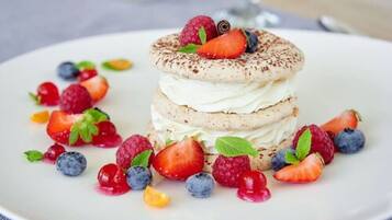 A dessert with multiple layers and topped with berries and mint leaves.
