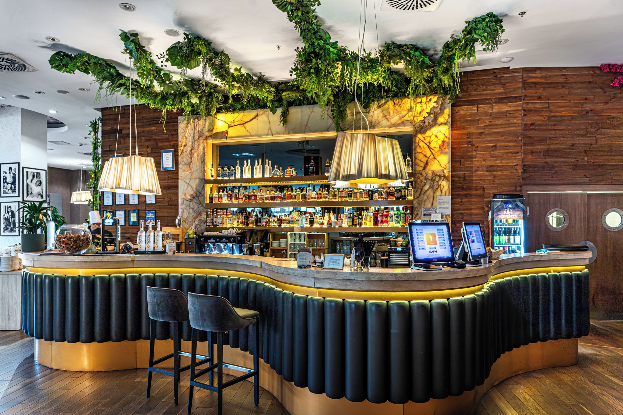 A bar area with a curved counter, bar stools, and a variety of liquor bottles.