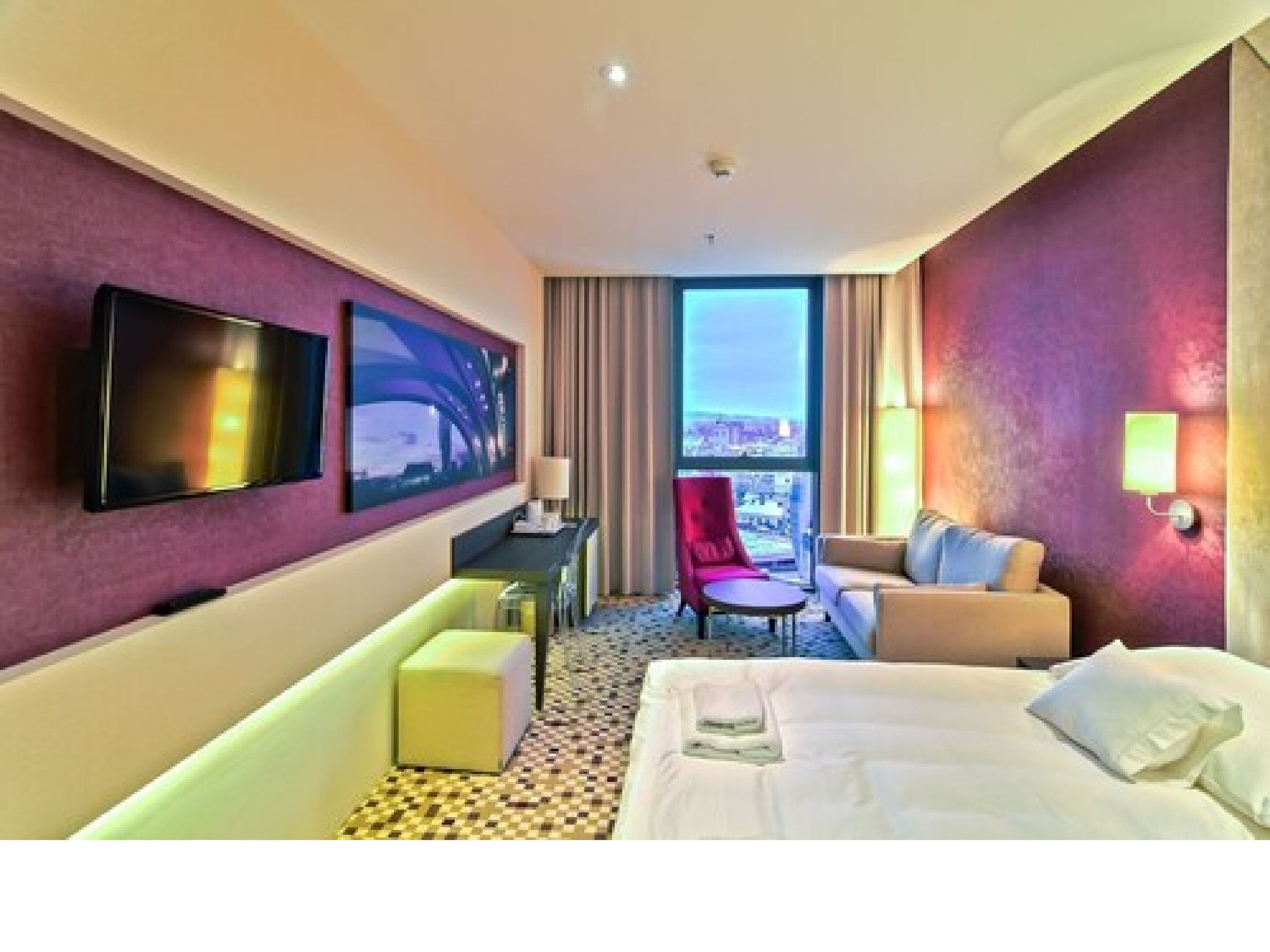 Ein Hotelzimmer mit einem Bett, einem Schreibtisch, einem Stuhl und einem Fernseher.
