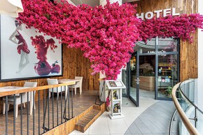 A hotel interior with a wooden wall, a large poster, a table with chairs, and a staircase leading to the entrance. - Hotel Rzeszów (Rzeszów)
