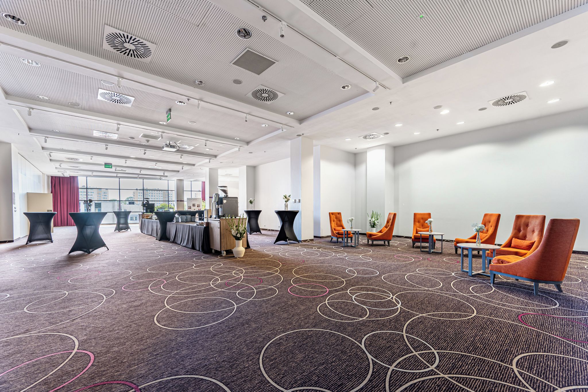 A spacious conference room with a high ceiling, modern lighting, and a carpet with circular patterns.