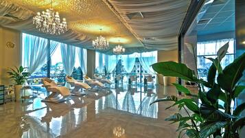 A spacious lobby with a reflective floor, large windows, and a chandelier.
