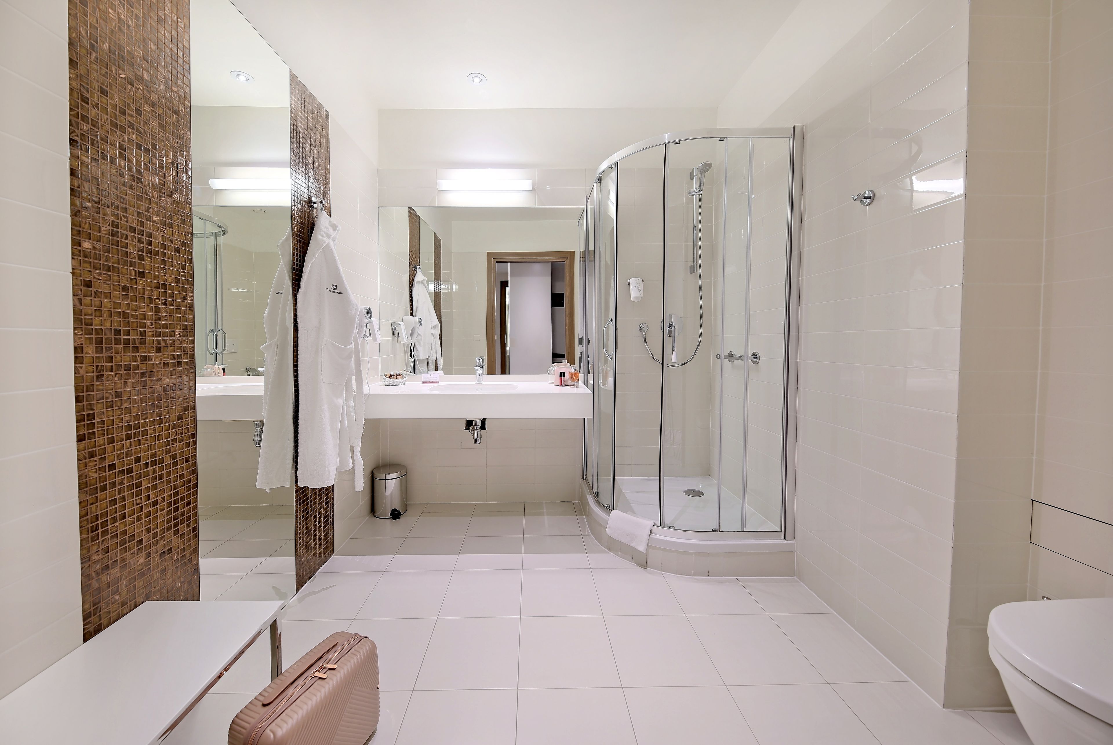 Un baño moderno con ducha envuelta en vidrio, un lavabo blanco y un espejo grande.