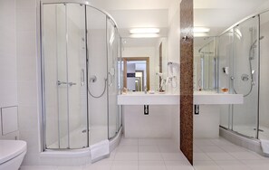 A modern bathroom with a glass-enclosed shower, a vanity with a mirror, and a toilet. - Hotel Rzeszów (Rzeszów)