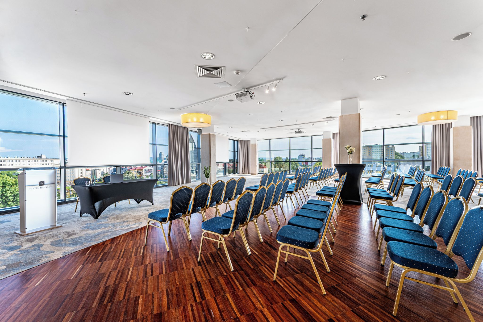 A conference room with rows of chairs, a podium, and a desk with a computer.