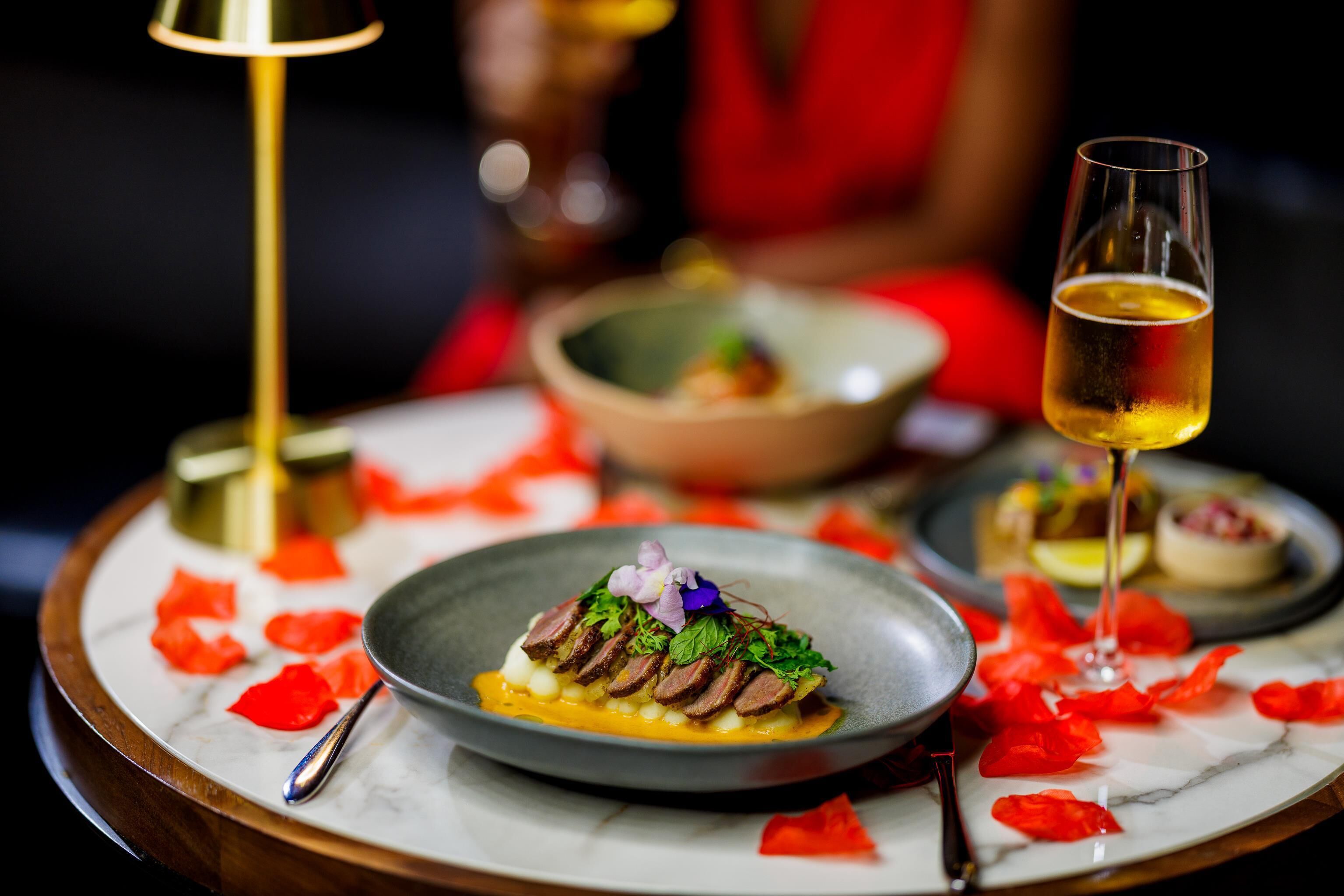 A dining table with a plate of food, a glass of wine, and a candle.