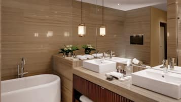 A modern bathroom with two sinks, a bathtub, and a vanity with toiletries.