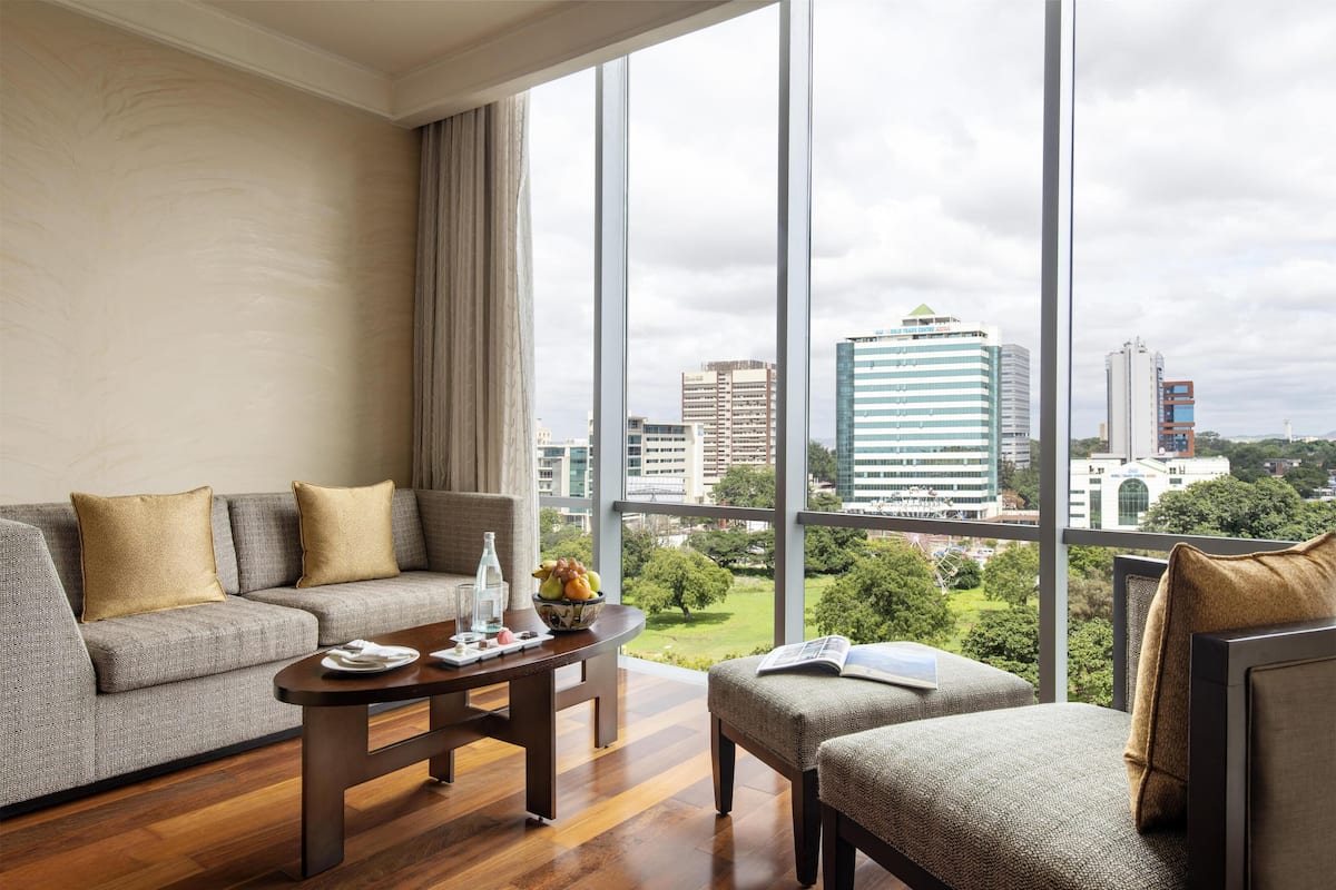 Ein modernes Wohnzimmer mit Sofa, Sessel und Couchtisch, mit Blick auf die Stadt durch große Fenster.