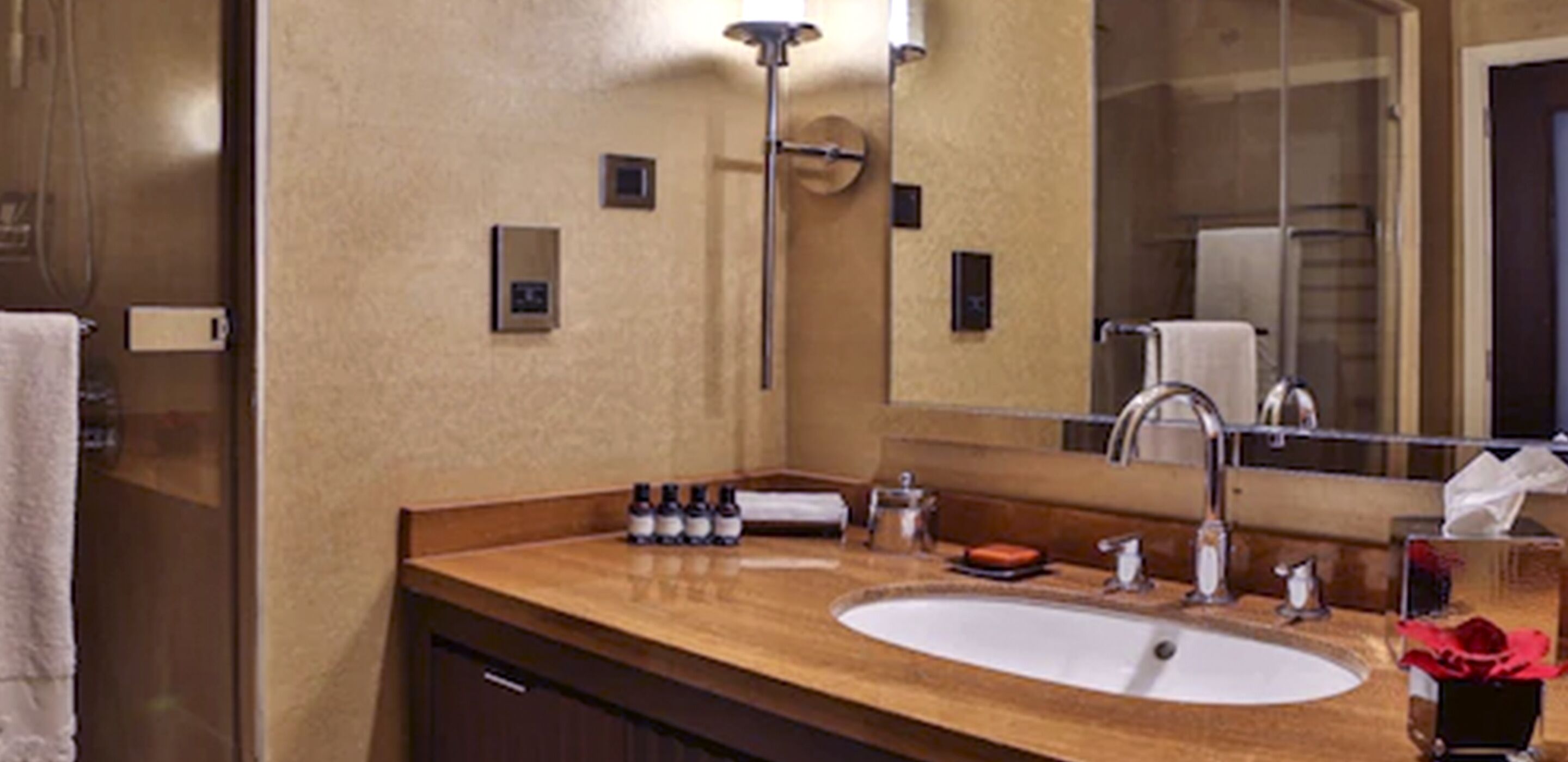 A hotel bathroom with a large sink, mirror, and towel rack.