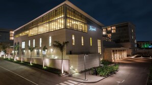 Een modern hotel met een glazen gevel, een zichtbaar naamteken en een goed verlicht entreegebied.