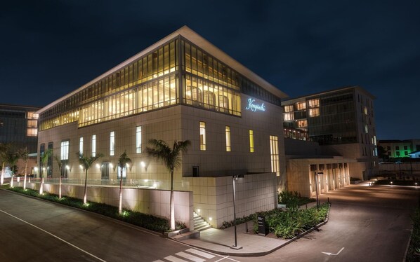 Un hôtel moderne doté d’une façade en verre, d’une enseigne bien visible et d’un hall d’entrée bien éclairé.