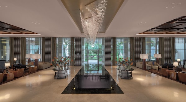 A spacious lobby with a reflective floor, a central table with vases, and a chandelier. - Kempinski Hotel Gold Coast City (Accra)