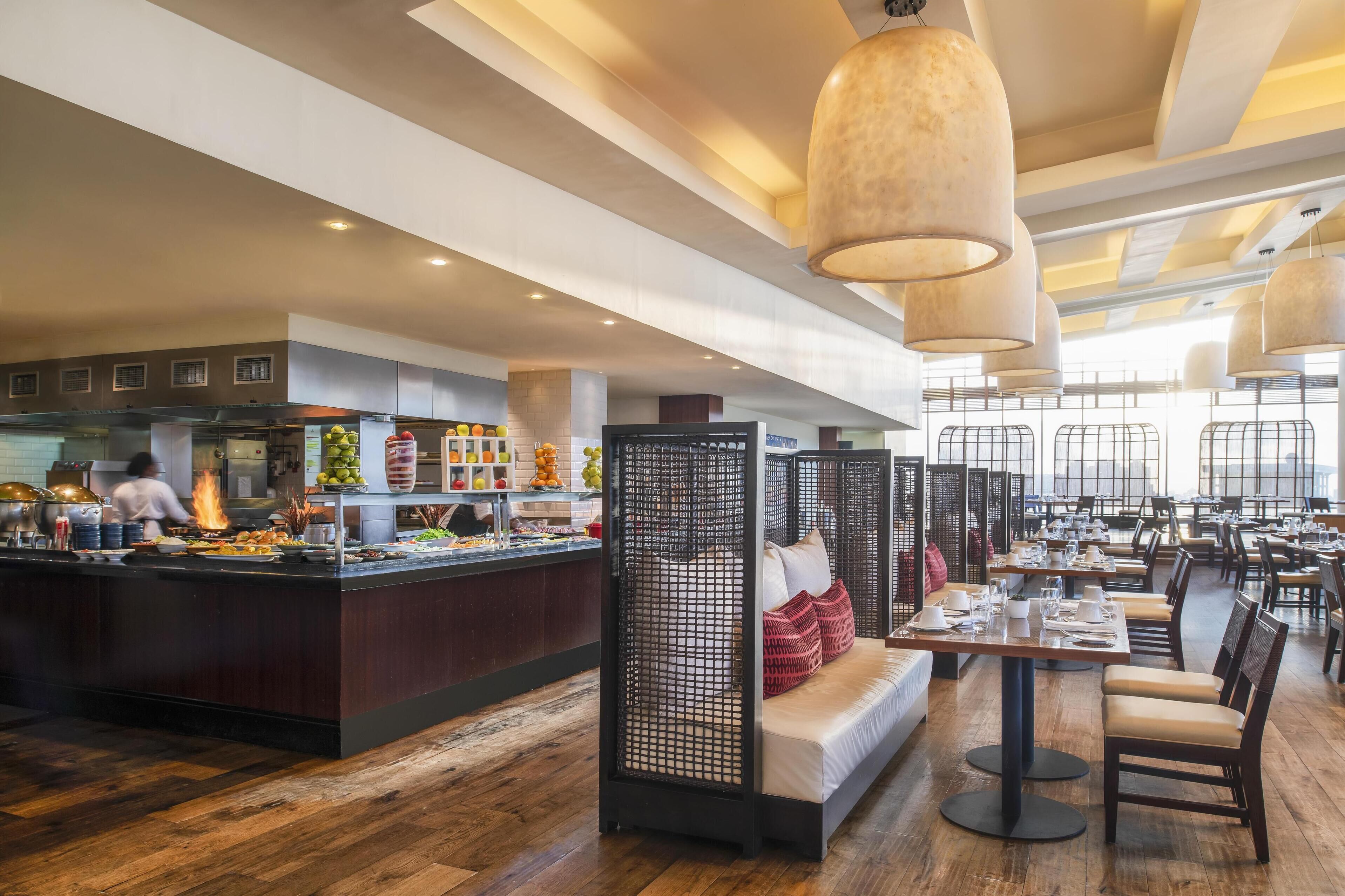 A restaurant with a central bar area, seating arrangements, and a modern interior design.