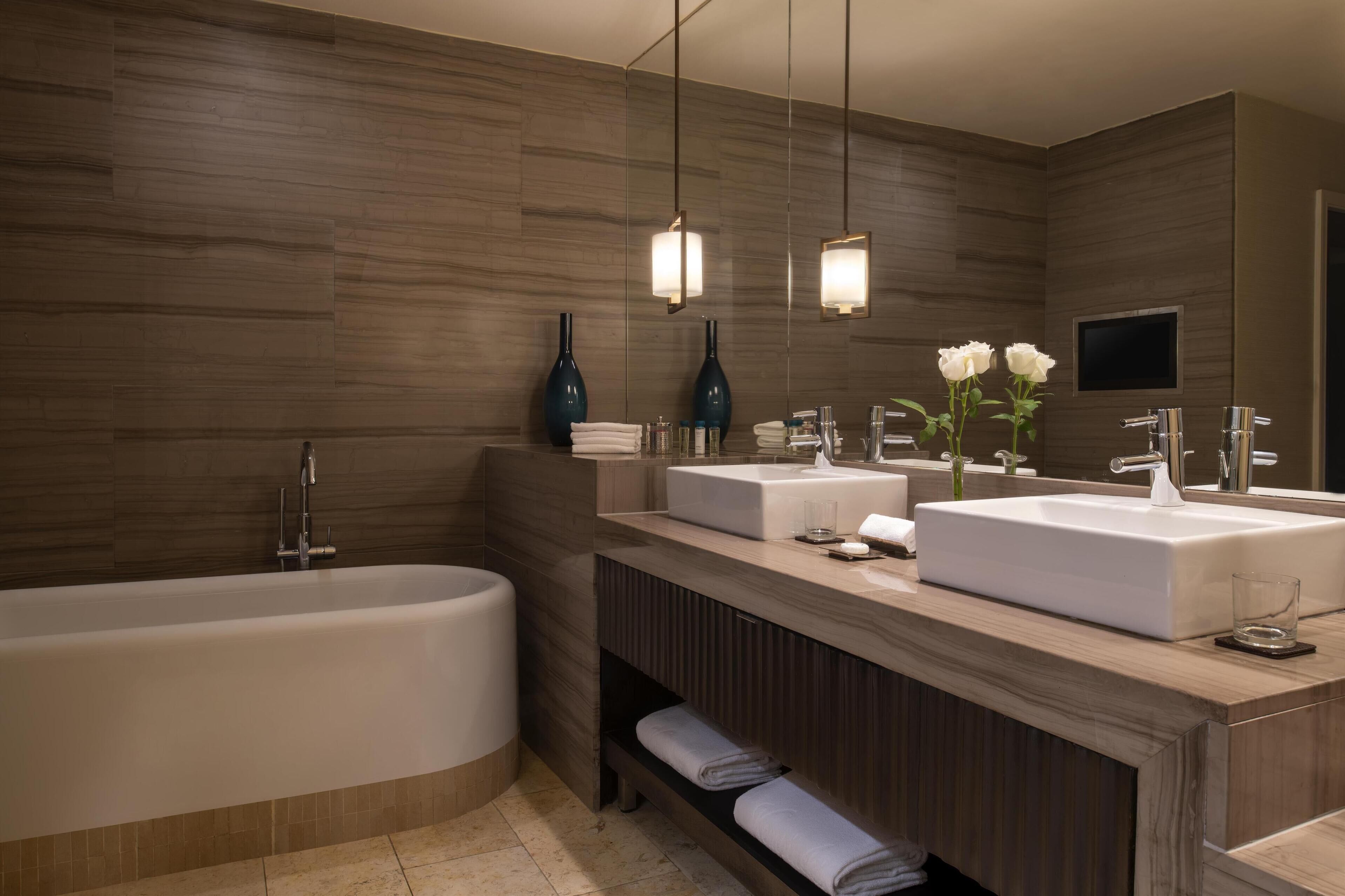 Une salle de bain moderne avec une baignoire sur pieds, deux vasques et un grand miroir.